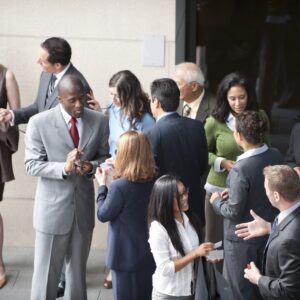 At a networking event, a group of professionals in business attire are mingling, exchanging business cards, and discussing Lorem Ipsum.