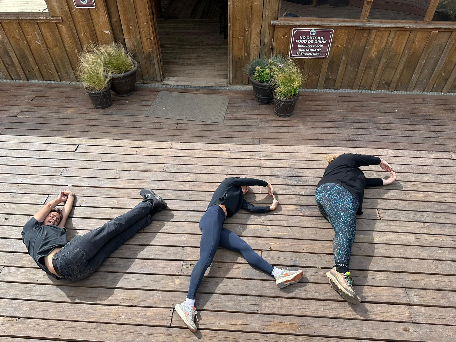 Three people laying on the ground with their heads down