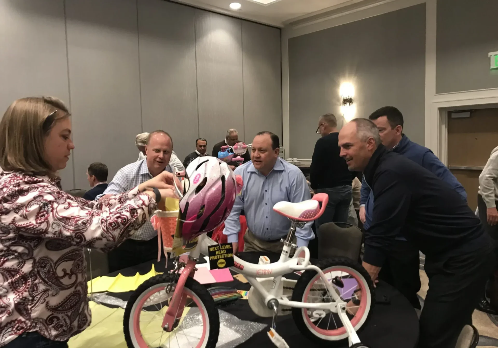People assembling children's bicycles at event.